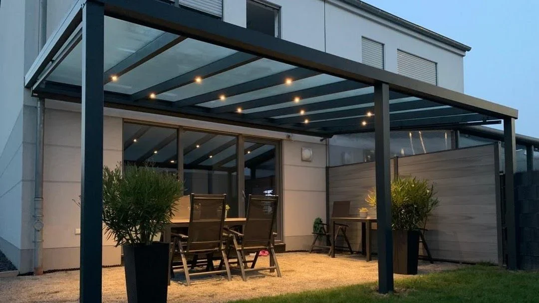 Beleuchtetes anthrazitfarbenes Terrassendach an einem modernen Wohnhaus